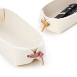Closeup of two white remote control caddies in pure wool felt when pink and yellow leather toggles